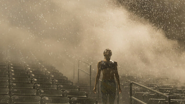 Female running athlete training on bleachers in rain